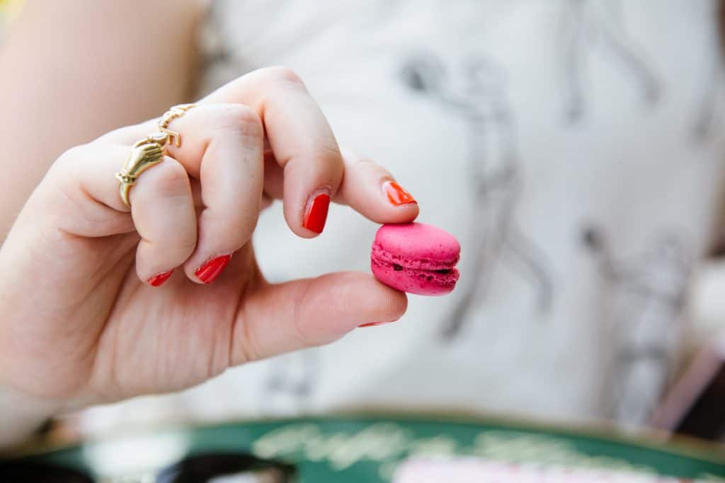 woman holding pink macaron in her hand