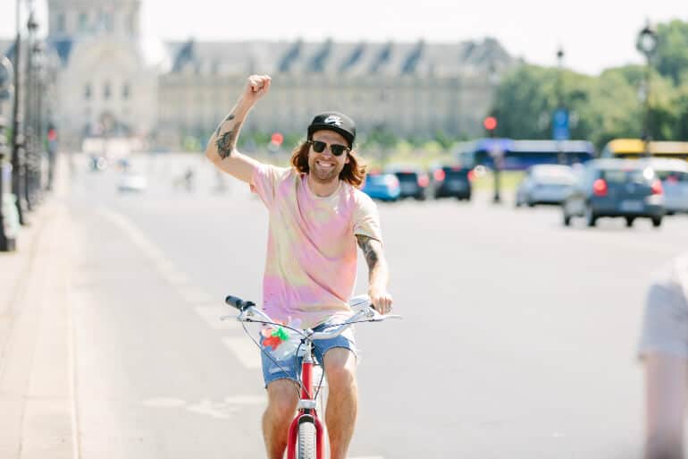 Man riding a bicycle fist pumps in Paris, France