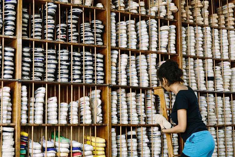 Woman in espadrilles shop restocks shelves in Barcelona, Spain.