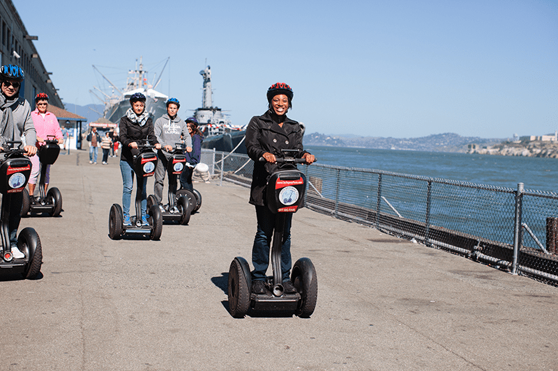 Woman smiles as she rides a Segway along the pier in San Francisco, California