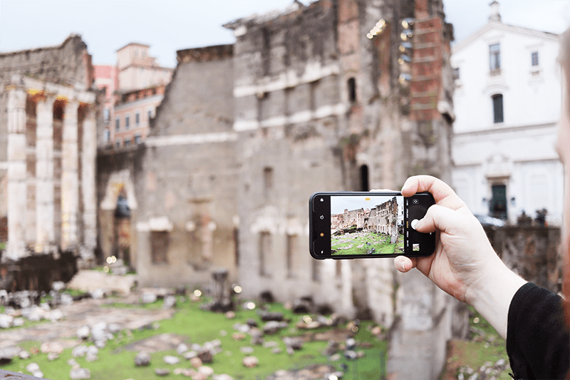 Close up of a person's hand taking a photo of Roman ruins in the Roman Forum on their iPhone.