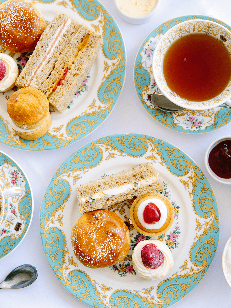 Flat lay of an afternoon tea spread from the Orangery at Kensington Palace's Afternoon Tea including cakes, scones, and tea.