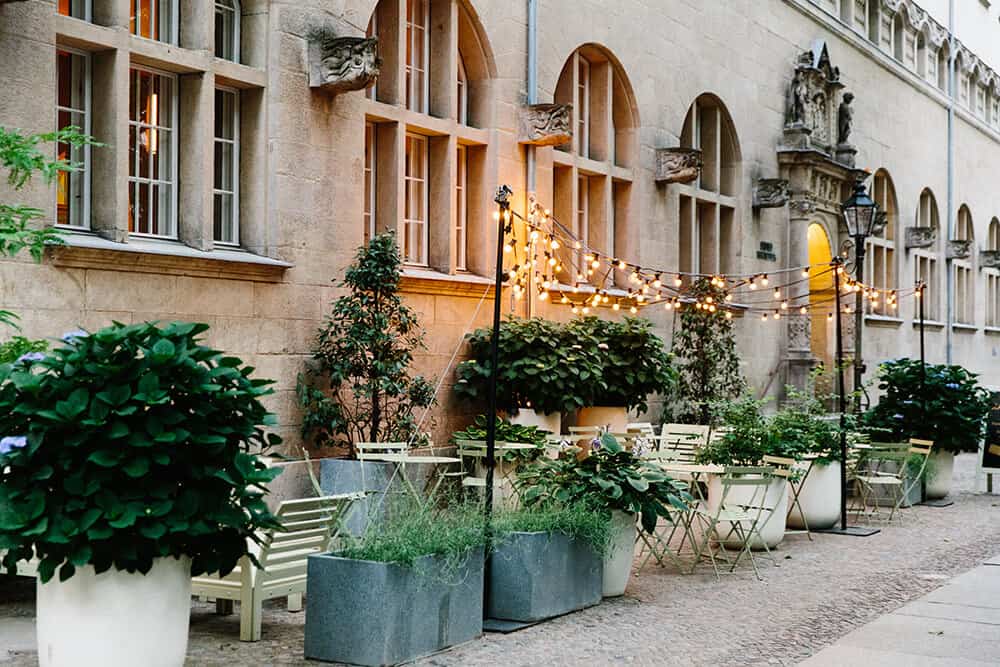 Greenery and lights hang above a patio of a restaurant in Berlin.