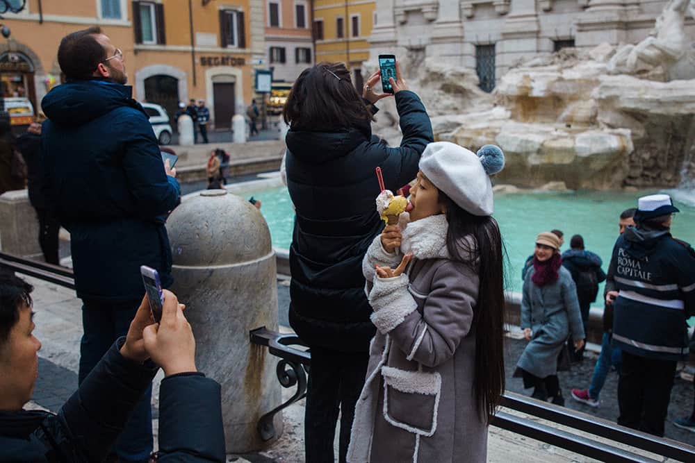 little girl eating gelato in front of trevi fountain in rome