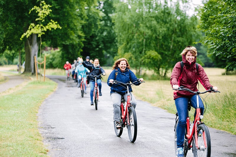 Line of people on bicycles smiling and laughing in Potsdam, Germany outside of Berlin.