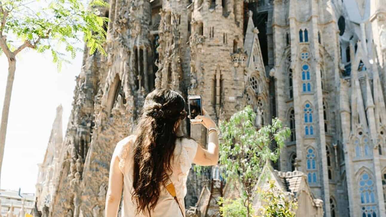 A woman takes a picture of the Sagrada Familia in Barcelona, Spain