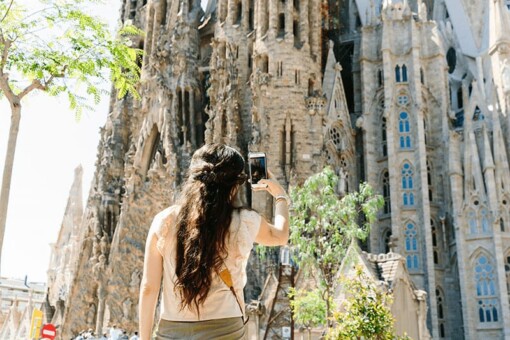 A woman takes a picture of the Sagrada Familia in Barcelona, Spain