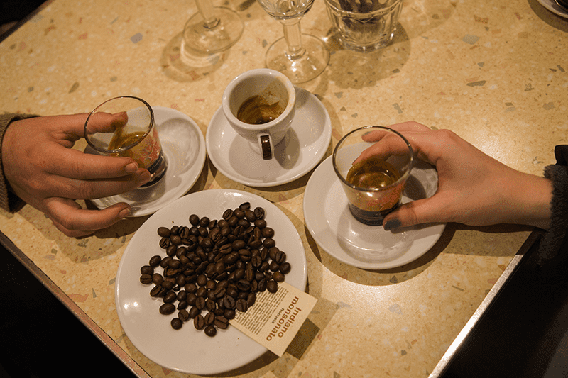 People hold espresso cups at a coffee tasting table in Italy