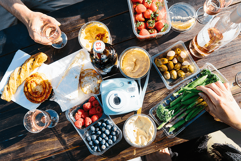 Aerial view of a wooden picnic table with vegetables, cider, and more