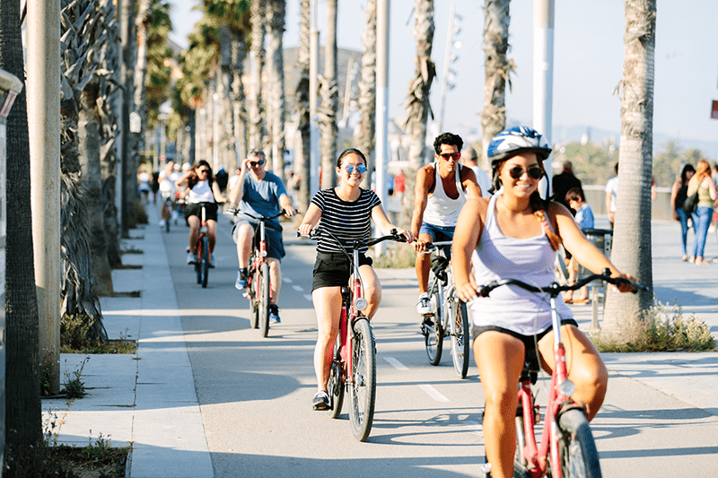 A line of people riding bikes along the beachfront in Barcelona, Spain