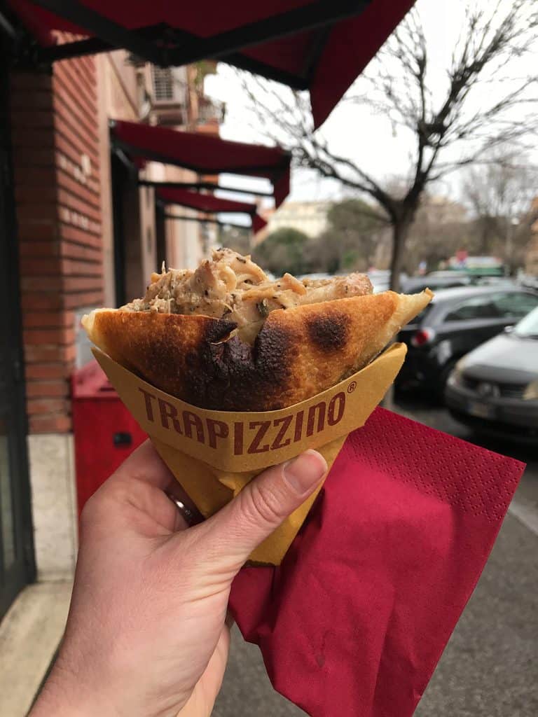 a hand holding up a Trapizzino in rome, italy