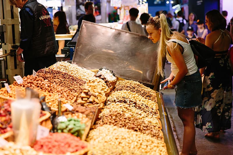 A woman looks closely at a food stall in Barcelona's famous La Boqueria food market