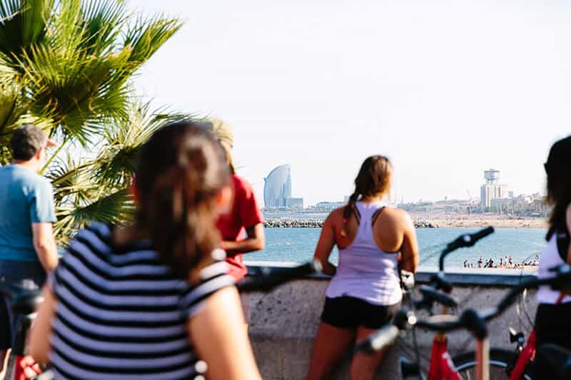 People on a bike tour in Barcelona, Spain look over the beach with the W Hotel in the distance