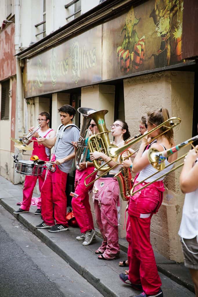 People wearing pink trousers play instruments in the streets of Paris, France during Fête de la Musique