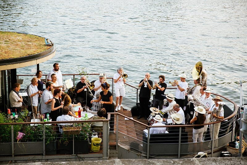 An orchestra plays instruments on a boat on the River Seine, Paris during Fête de la Musique
