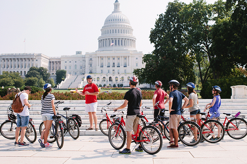 A tour group on bicycles stops to listen to their tour guide in front of the U.S. Capitol Building in Washington, D.C.