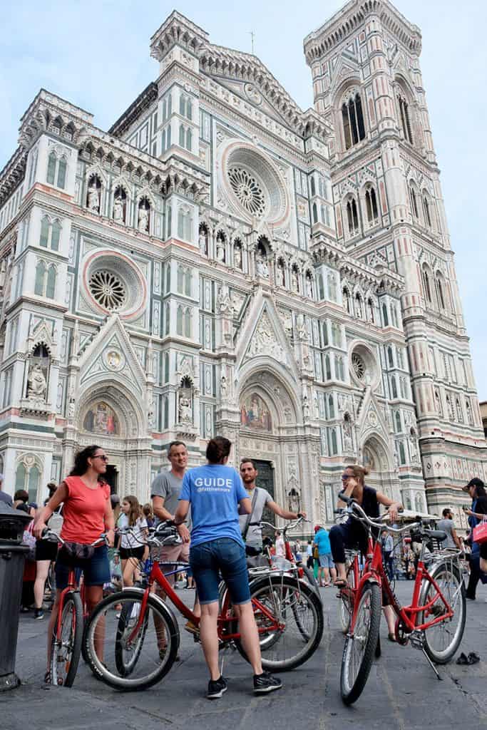 Tour group on bicycles in front of the facade of the Duomo di Firenze in Florence, Italy