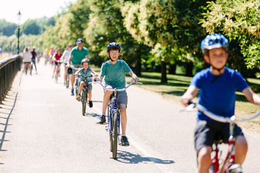 People riding their bikes through Hyde Park in London, England