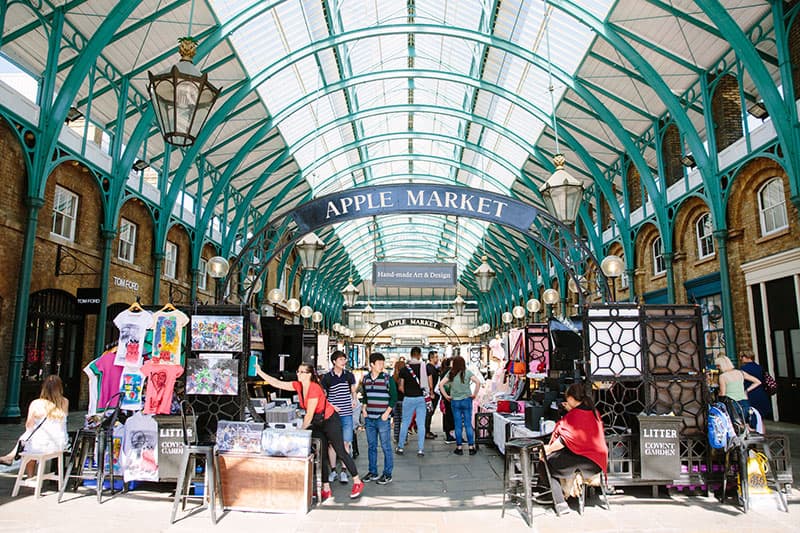 A covered market in London with a sign for an Apple Market