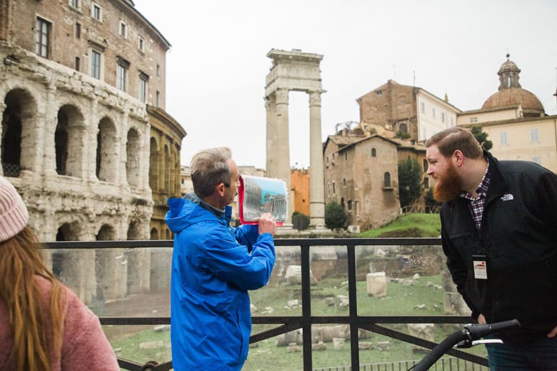 Tour guide pointing to a historical rendering of the Colosseum in Rome, Italy