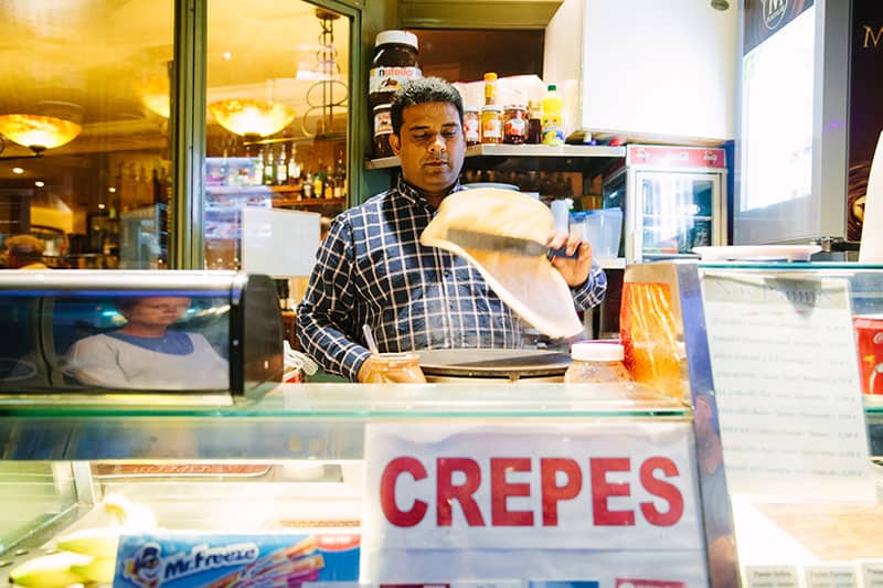 Man prepares crepes at a crepe stand in Paris, France
