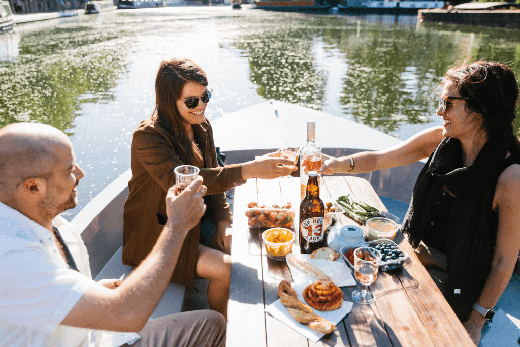 Friends smile while enjoying a picnic on Regent's Canal, London