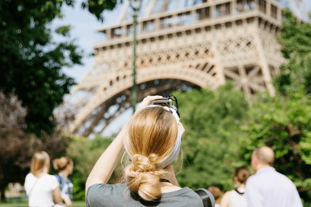 Woman with blonde hair takes a photo of the Eiffel Tower in Paris, France.
