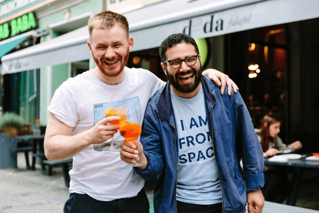 Two men laugh while holding margaritas