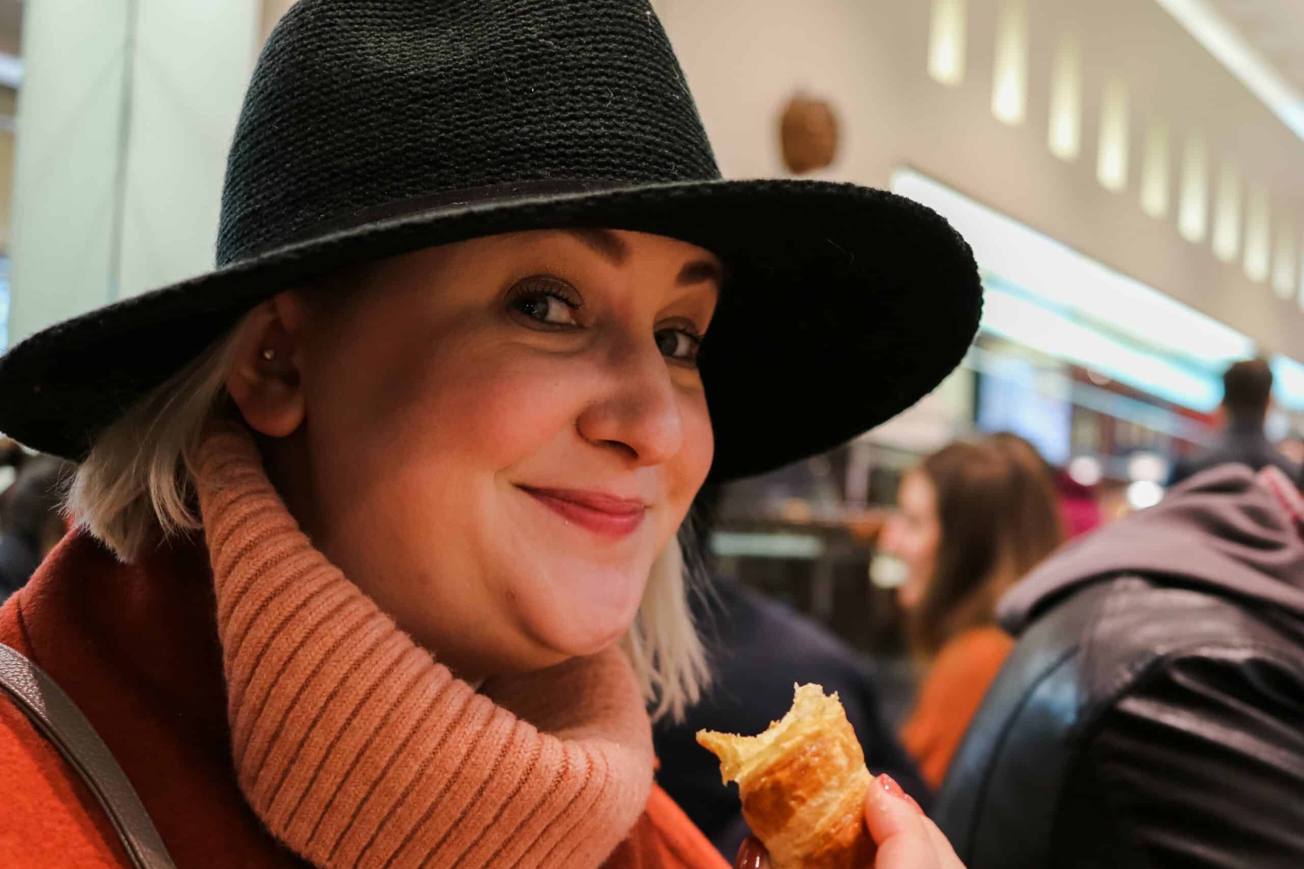 A woman smiles as she enjoys an Italian pastry in Milan