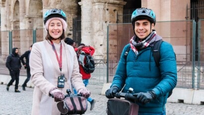 Two people pose for a photo on Segways in front of the Colosseum in Rome, Italy