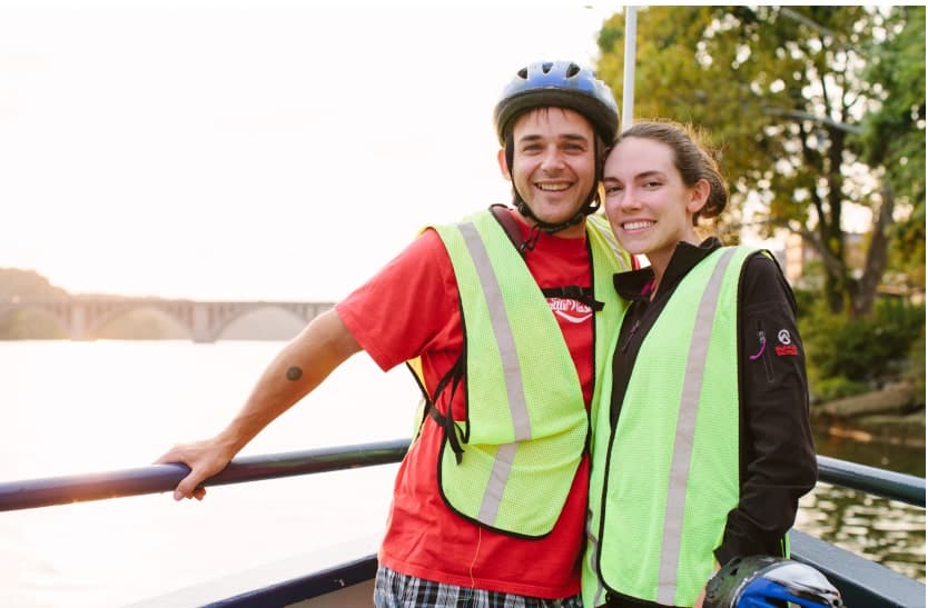 two people posing for a photo along the potomac in front of the francis scott key bridge