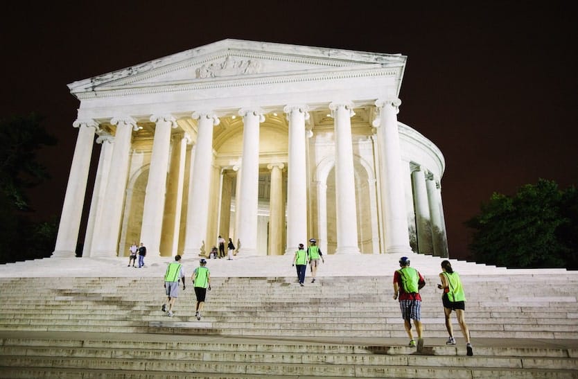 people in reflective vests walking up the stairs to the lincoln memorial at night