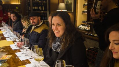 A woman leans forward and smiles during the wine tasting portion of the Florence Evening Food Tour in Italy