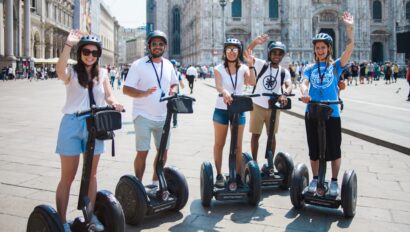 A group waves while riding Segways in front of the Duomo in Milan, Italy