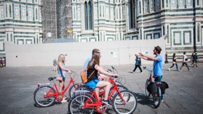 A guide explains the surrounding sites to a group on bikes near the Duomo in Florence, Italy