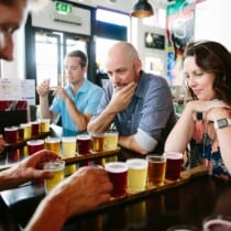 A couple looks at a flight of beer as the guide explains it in London, England