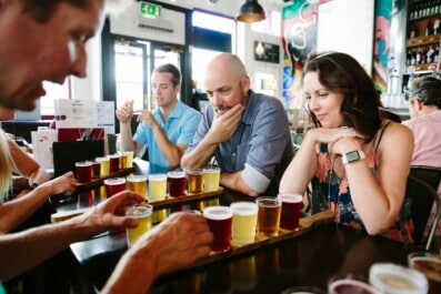 A couple looks at a flight of beer as the guide explains it in London, England