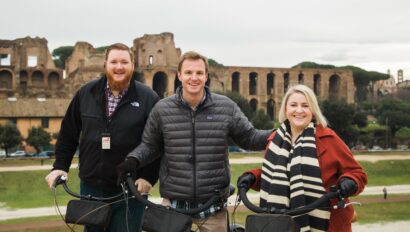 A group poses with their bikes in front of the Colosseum in Rome, Italy