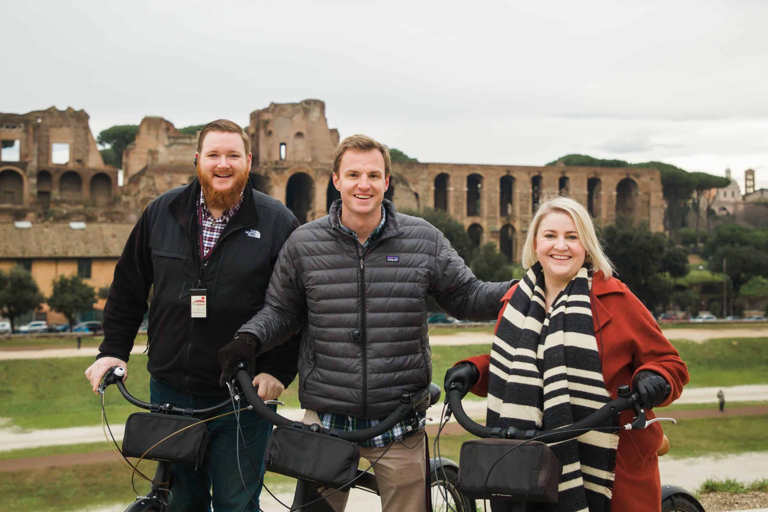 A group poses with their bikes in front of the Colosseum in Rome, Italy