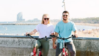 A couple poses on their bikes in front of the Barceloneta beach in Barcelona, Spain