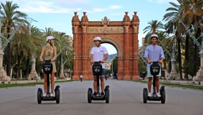 Three people ride Segways in front of the Arc de Triomf in Barcelona, Spain
