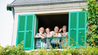 A group of four women smile and wave from Claude Monet's house in Giverny, France