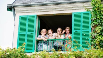 A group of four women smile and wave from Claude Monet's house in Giverny, France