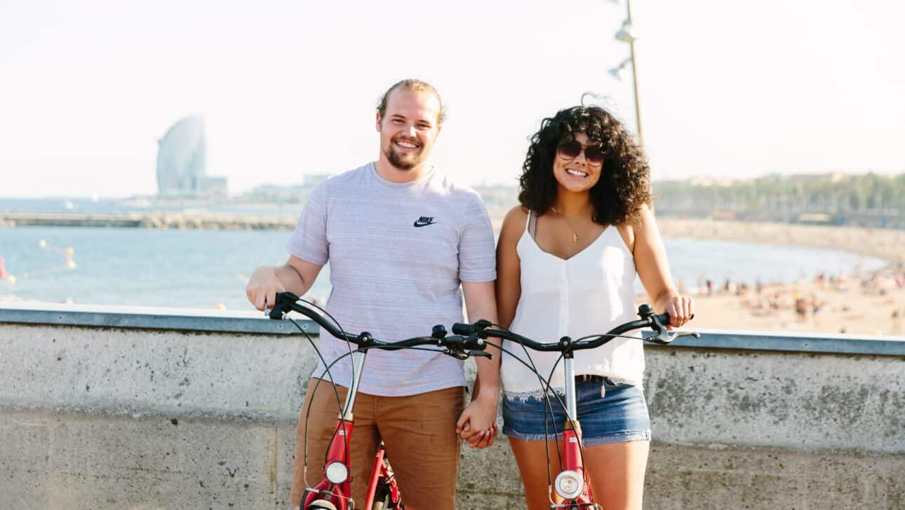 A couple poses with their bikes near the Barcelona Beach in Barcelona, Spain