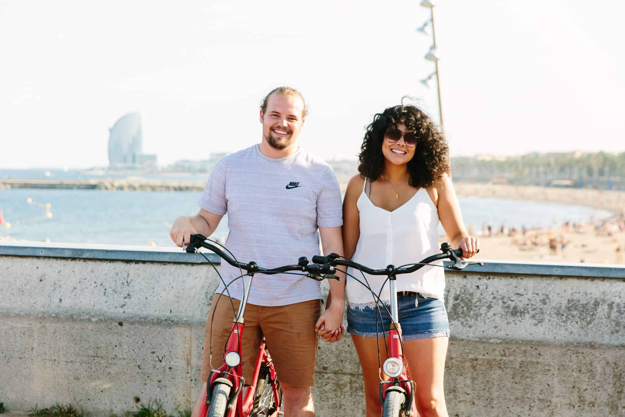 A couple poses with their bikes near the Barcelona Beach in Barcelona, Spain