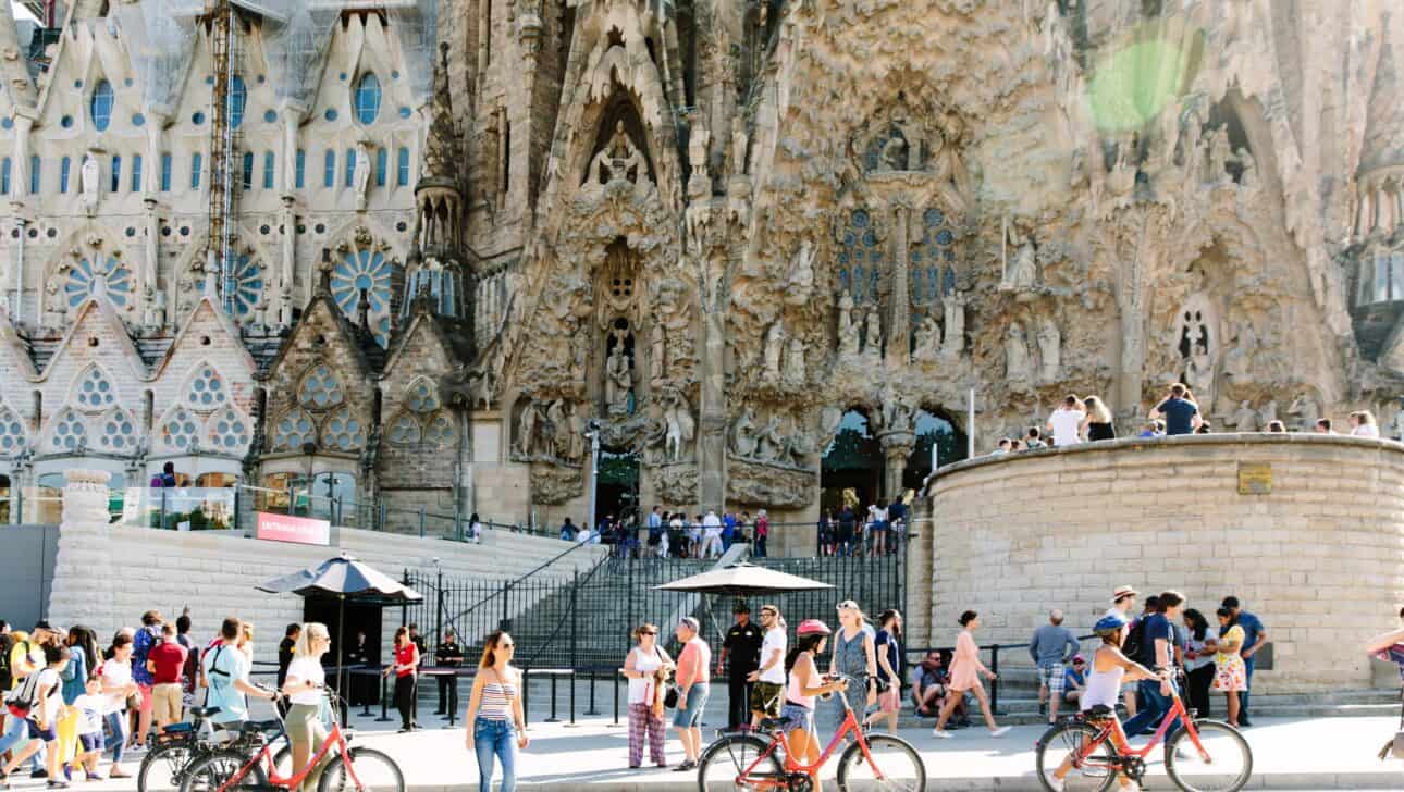 A group pushes their bikes in front of the Sagrada Familia in Barcelona, Spain