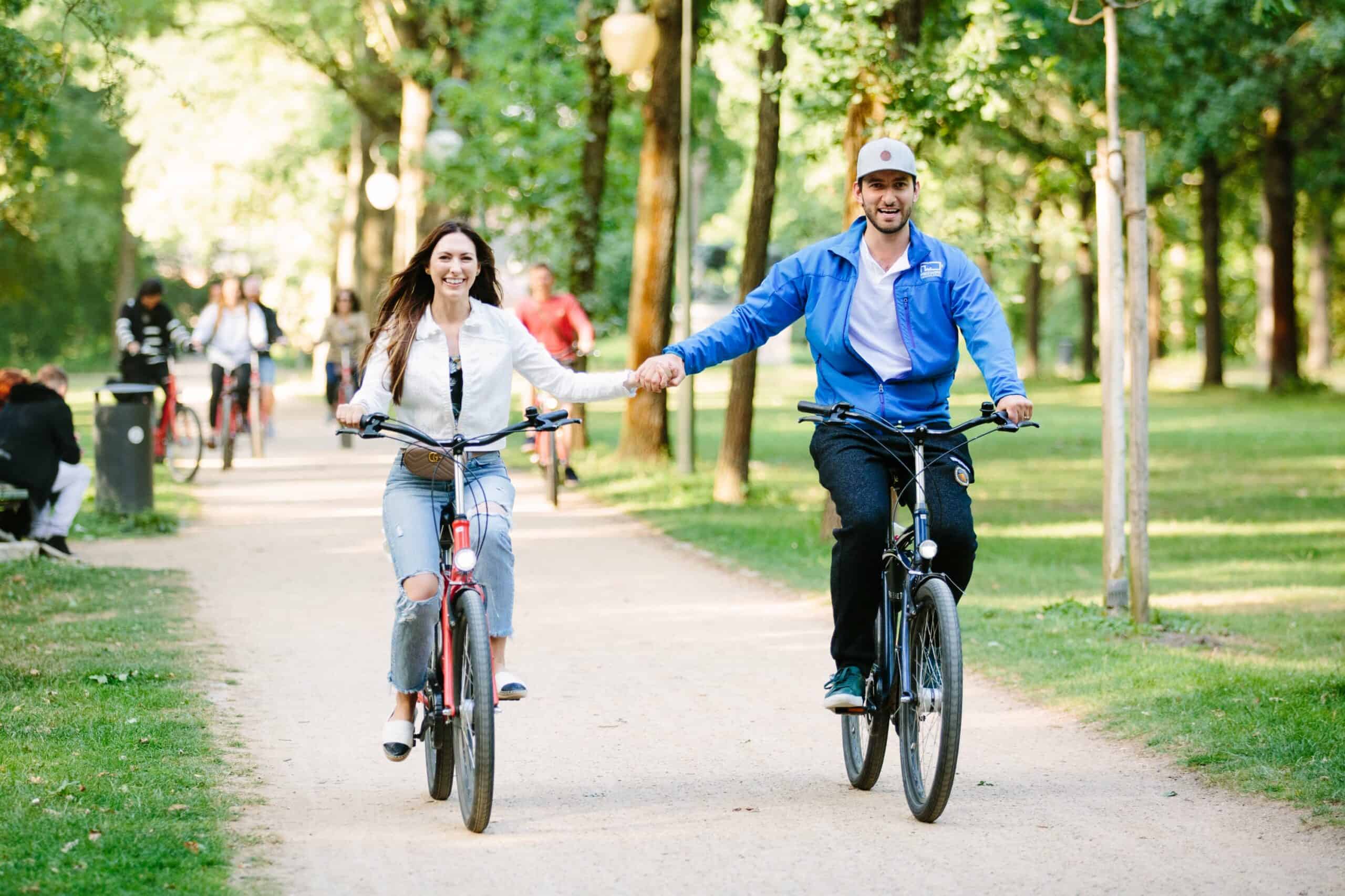 Two people hold hands while riding through the Tiergarten in Berlin, Germany