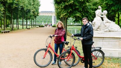 Two people pose with their bikes behind Sansoucci Palace in Potsdam, Germany