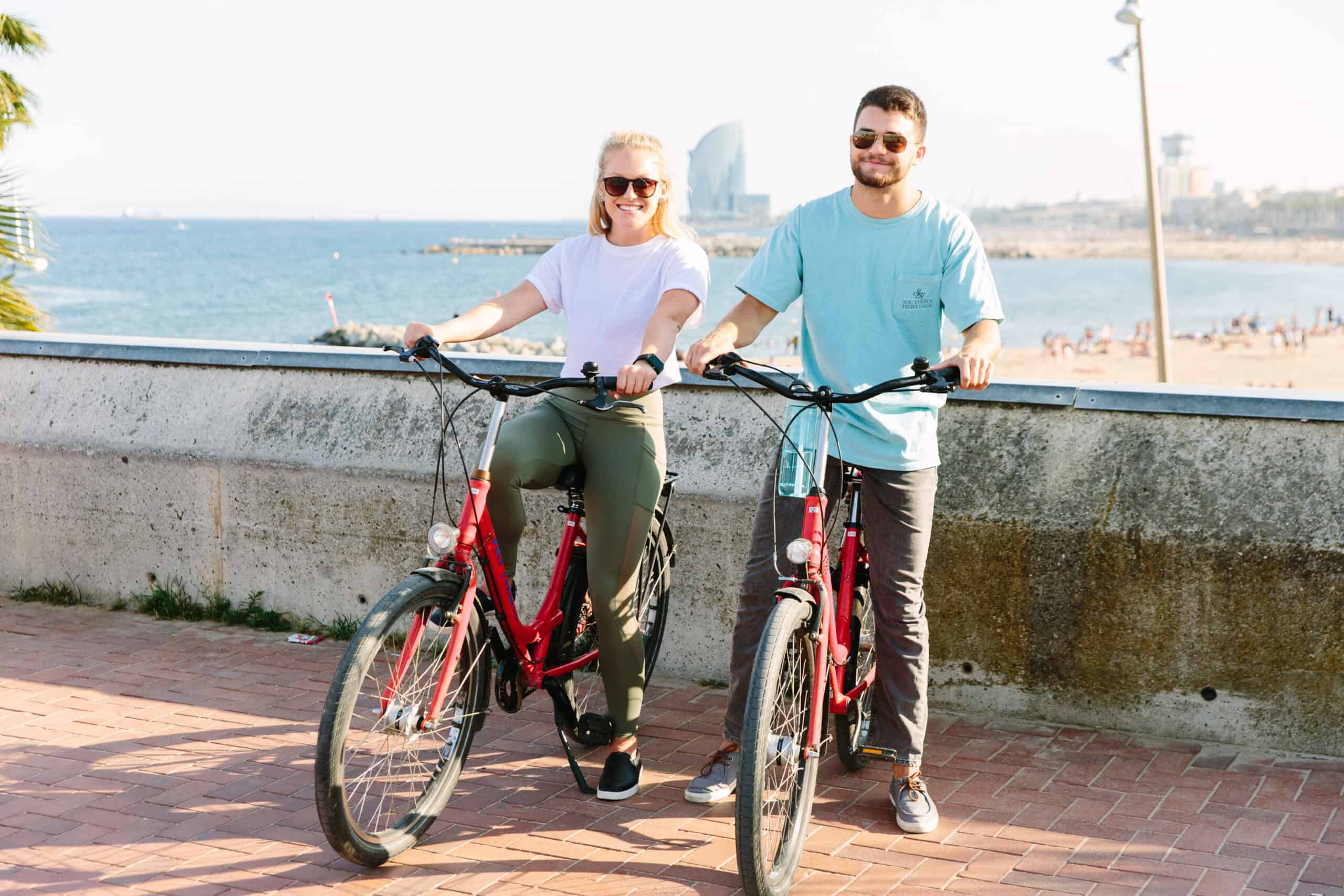 A couple poses with their bikes by the Barceloneta Beach in Barcelona, Spain