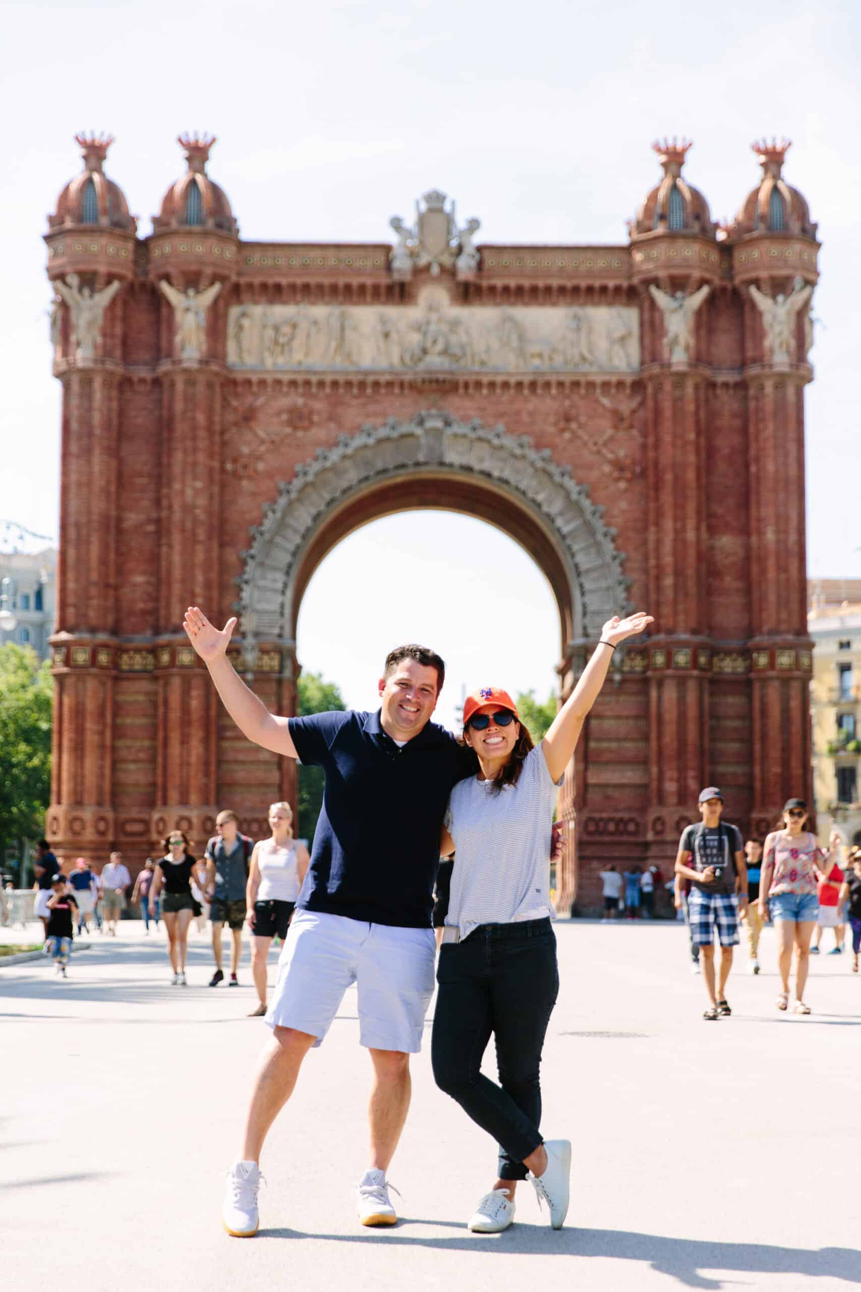 A couple poses for a photo in front of the Arc de Triomf in Barcelona, Spain